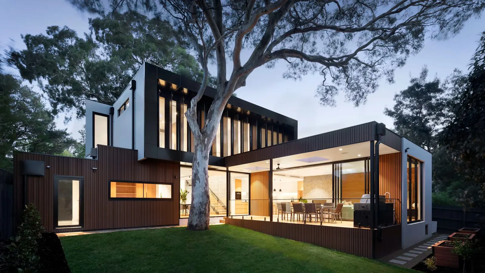 Modern house with open-plan living and a timber ceiling at dusk
